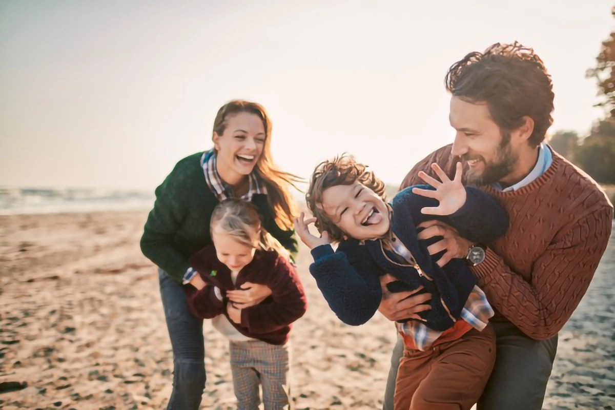Image of a young family playing on the beach